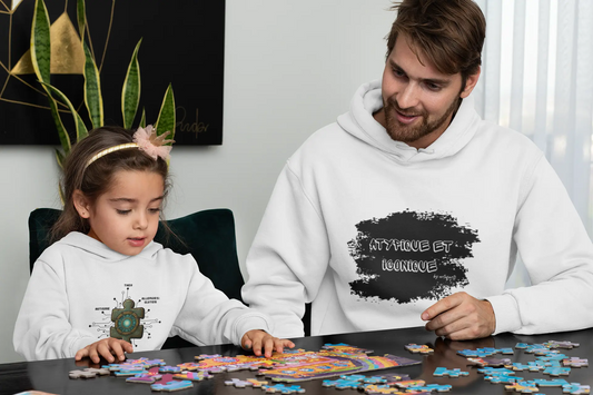 Père et fille portant des hoodies Artefacts blancs personnalisés, jouant à un puzzle ensemble à la maison.